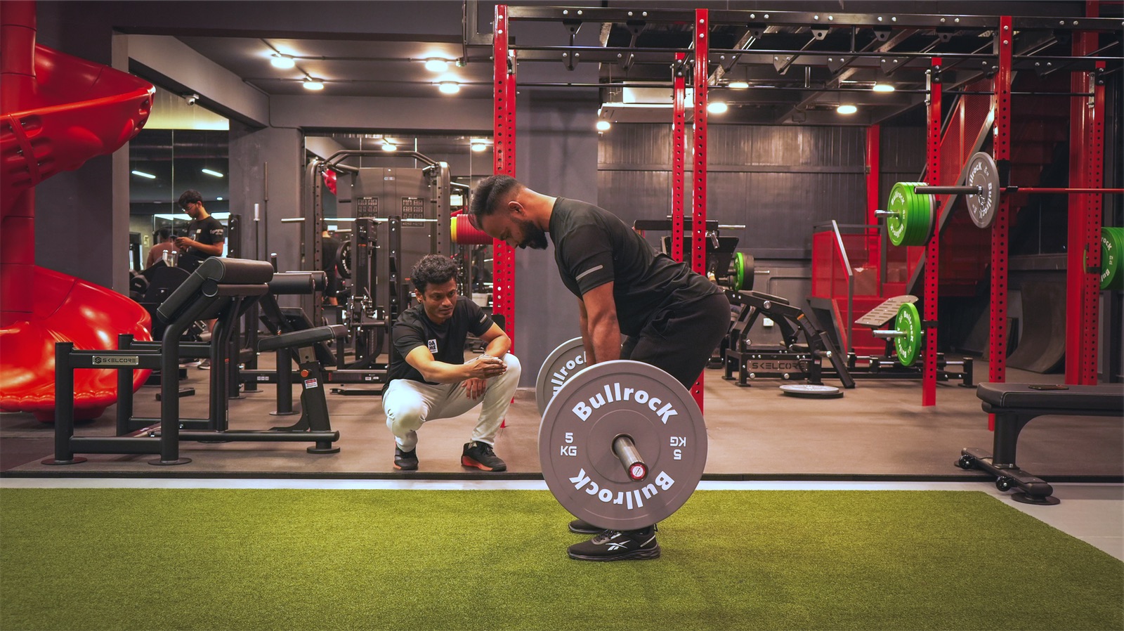 A Game Theory trainer coaching a member through a deadlift at the Indiranagar gym