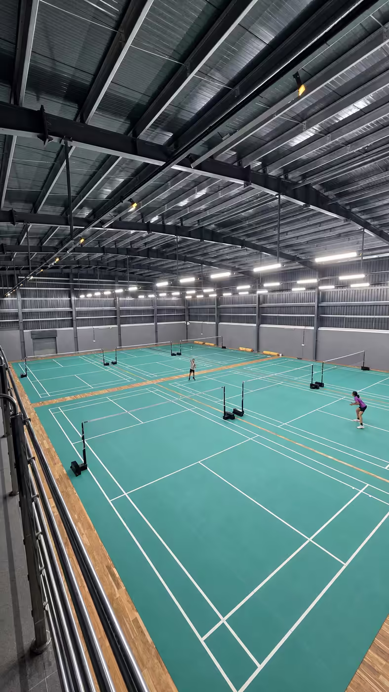 A player mid-rally on the red BWF-approved badminton courts at Game Theory Panathur